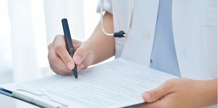 Bildausschnitt Arztkittel und Hand mit Stift und Checkliste